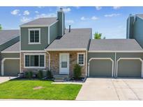 Charming home featuring stone accents, green siding, an attached two-car garage, and a well-manicured lawn at 4750 S Dudley St # 21, Littleton, CO 80123