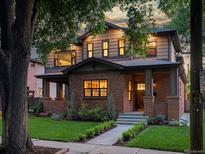 Charming two-story brick home featuring a well-maintained lawn, landscaped flower beds and a covered porch at 1051 S York St, Denver, CO 80209