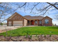 Charming single-Gathering home featuring a brick facade, well-manicured lawn, and a three-car garage at 16350 Timber Cove St, Hudson, CO 80642