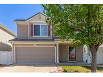 Two-story home featuring a two-car garage and charming curb appeal with fresh green landscaping and brick-lined driveway at 5538 Espana Ct, Denver, CO 80249