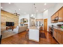 Open concept living space featuring a kitchen island, hardwood floors, and a cozy fireplace at 14434 W 88Th Dr # B, Arvada, CO 80005