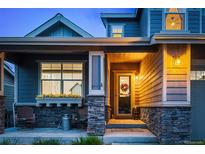 Charming covered front entrance with stone accents and colorful flower display on the window and door at 4738 Colorado River Dr, Firestone, CO 80504