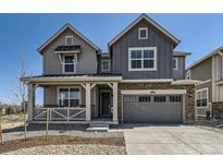 Charming two-story home with gray siding, stone accents, a covered porch, and a two car garage at 10720 Snowdon St, Parker, CO 80134