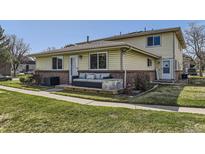 Charming exterior view of home with yellow siding, brick accents, and a cozy front porch with stylish outdoor seating at 3225 S Garrison St # 9, Lakewood, CO 80227