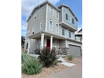 Charming three-story home featuring a covered front porch and attached two-car garage at 16362 E 111Th Dr, Commerce City, CO 80022
