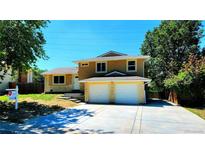 Two-story home with a two-car garage, yellow paint, stone accents and well-kept lawn and landscaping at 16800 E Bails Pl, Aurora, CO 80017