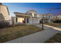 Charming gray two-story home with covered porch and well-maintained lawn at 5202 Cathay St, Denver, CO 80249