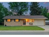 Charming ranch home features a well-manicured front lawn, brick facade, and attached one-car garage at 10844 W 68Th Ave, Arvada, CO 80004