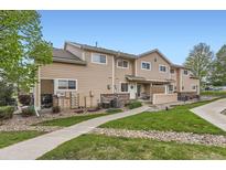 Inviting exterior view of tan two-story townhome, showcasing landscaped front yard and cozy outdoor space at 1601 Great Western Dr # D3, Longmont, CO 80501