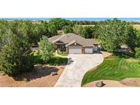 Beautiful home boasts mature trees, lush lawn, and a long driveway leading to an attached three-car garage at 6297 E 167Th Ave, Brighton, CO 80602