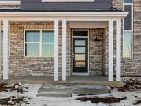 Exterior of house with stone facade, covered porch, and white columns at 22290 E 8Th Pl, Aurora, CO 80018