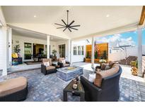 Inviting covered patio with a fire pit, comfortable seating, and stylish ceiling fan at 5707 Cadara Way, Parker, CO 80134