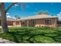 Charming brick home with a well-maintained lawn, mature trees, and an inviting facade at 1077 Salem St, Aurora, CO 80011