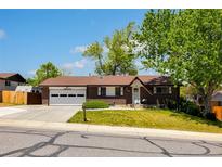 Charming brick home with attached two-car garage and well-manicured front lawn under a clear blue sky at 12771 W 6Th Pl, Lakewood, CO 80401