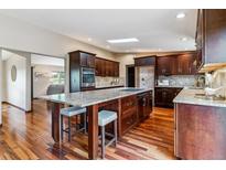 Open kitchen boasts dark wood cabinetry, granite countertops, stainless steel appliances, and a spacious island at 40192 Margaret Dr, Elizabeth, CO 80107