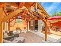 Inviting backyard features a wooden pergola, brick patio, and a charming outdoor dining space at 12433 Bellaire Dr, Thornton, CO 80241