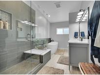 Modern bathroom featuring a glass shower, soaking tub, double vanity, and neutral color palette at 12433 Bellaire Dr, Thornton, CO 80241