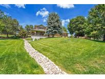 Beautiful two-story home featuring mature trees and a large manicured lawn in a serene landscape at 25741 E Kettle Cir, Aurora, CO 80016