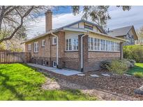 Brick home with an enclosed sunroom featuring ample windows and a well-maintained lawn at 1230 S Emerson St Dr, Denver, CO 80210