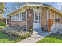 Charming brick home features a white-framed glass door and sunroom with a well-manicured lawn at 1230 S Emerson St Dr, Denver, CO 80210