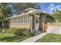 Charming brick home featuring a sunroom with ample windows and a well-maintained front yard at 1230 S Emerson St Dr, Denver, CO 80210