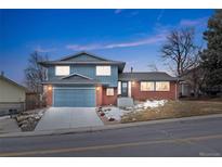 Two-story home features brick accents, an attached garage, and a well-maintained front yard at 1513 S Beech St, Lakewood, CO 80228