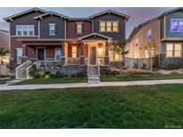 Inviting two-story townhome with a cozy front porch and lush green lawn at 13860 Ash Cir, Thornton, CO 80602