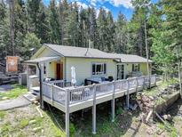 Charming home with a gray wood deck and patio furniture surrounded by lush greenery and tall trees at 8340 London Ln, Conifer, CO 80433