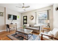 Bright living room features a grey sofa, ceiling fan, modern rug, and hardwood floors at 2645 W 24Th Ave, Denver, CO 80211