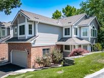 Charming two-story home featuring a brick facade, gray siding, attached garage, and mature landscaping at 7630 S Monaco Way, Centennial, CO 80112
