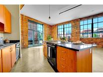 Bright, open kitchen features brick walls, stainless steel appliances, and a center island with a black countertop at 2500 Walnut St # 102, Denver, CO 80205