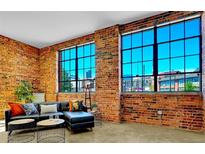 Bright living room featuring exposed brick walls, large windows, and stylish modern furnishings at 2500 Walnut St # 102, Denver, CO 80205