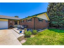 Charming brick home with green trim, lush lawn, and outdoor seating area at 10684 Downing St, Northglenn, CO 80233