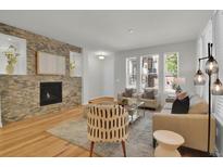 Bright living room featuring hardwood floors, a modern stone fireplace, and ample natural light at 5887 S Taft Ln, Littleton, CO 80127