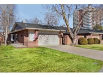 Charming brick home featuring an attached two-car garage, lush green lawn, and mature shade trees at 2552 E Alameda Ave # 104, Denver, CO 80209