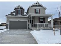 Two-story house with gray siding, a large garage, and a covered porch at 16592 E 109Th Ave, Commerce City, CO 80022