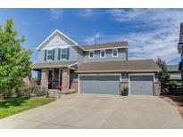 Charming two-story home featuring a three-car garage, inviting front porch, and manicured lawn on a sunny day at 4858 S Tibet St, Aurora, CO 80015
