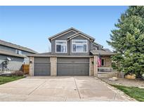 Two-story home featuring a three car garage, neutral paint, well maintained landscaping, and an American flag at 6530 S Tabor St, Littleton, CO 80127