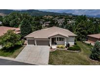 Stunning exterior view of home featuring a tile roof, three-car garage, and lush landscaping at 6379 Spotted Fawn Run, Littleton, CO 80125