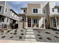 Inviting front exterior showcasing a modern townhouse with a landscaped yard and a striking red front door at 4594 S Versailles St # A, Aurora, CO 80015