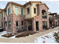 Exterior of charming 2-story townhome with stone accents and snowy landscape at 2198 Primo Rd # 103, Highlands Ranch, CO 80129
