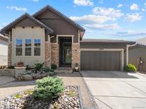 Charming home with a stone and siding exterior, a well-manicured front yard, and an attached two-car garage at 6268 Dakota Ridge Dr, Littleton, CO 80125