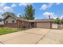 Ranch-style brick home featuring an attached garage, concrete driveway, and mature trees at 760 Dean Dr, Northglenn, CO 80233