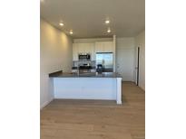 Modern kitchen featuring stainless steel appliances, gray countertops, and a breakfast bar with wood flooring at 6562 Arbor Blvd # 4, Thornton, CO 80602