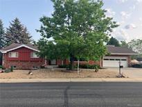 Charming brick home featuring a beautiful front yard with mature landscaping and attached two-car garage at 7105 Dover Way, Arvada, CO 80004