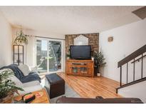 Bright living room featuring hardwood floors, a stone accent wall, and sliding glass doors to the outside at 3506 S Depew St # 3, Denver, CO 80235