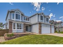 Charming two-story home with a three-car garage, manicured lawn, and brick accents at 10155 Silver Maple Cir, Highlands Ranch, CO 80129