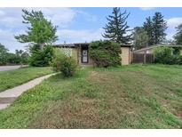 Charming brick home featuring a well-maintained front yard with mature trees and a walkway at 588 Empire St, Aurora, CO 80010