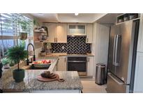 Bright kitchen featuring granite countertops, modern appliances, and stylish black and white tile backsplash at 442 S Carr St, Lakewood, CO 80226