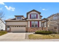 Charming two-story home with a stone accent, a well-manicured lawn and beautiful maroon shutters at 1533 Bellflower Dr, Brighton, CO 80601